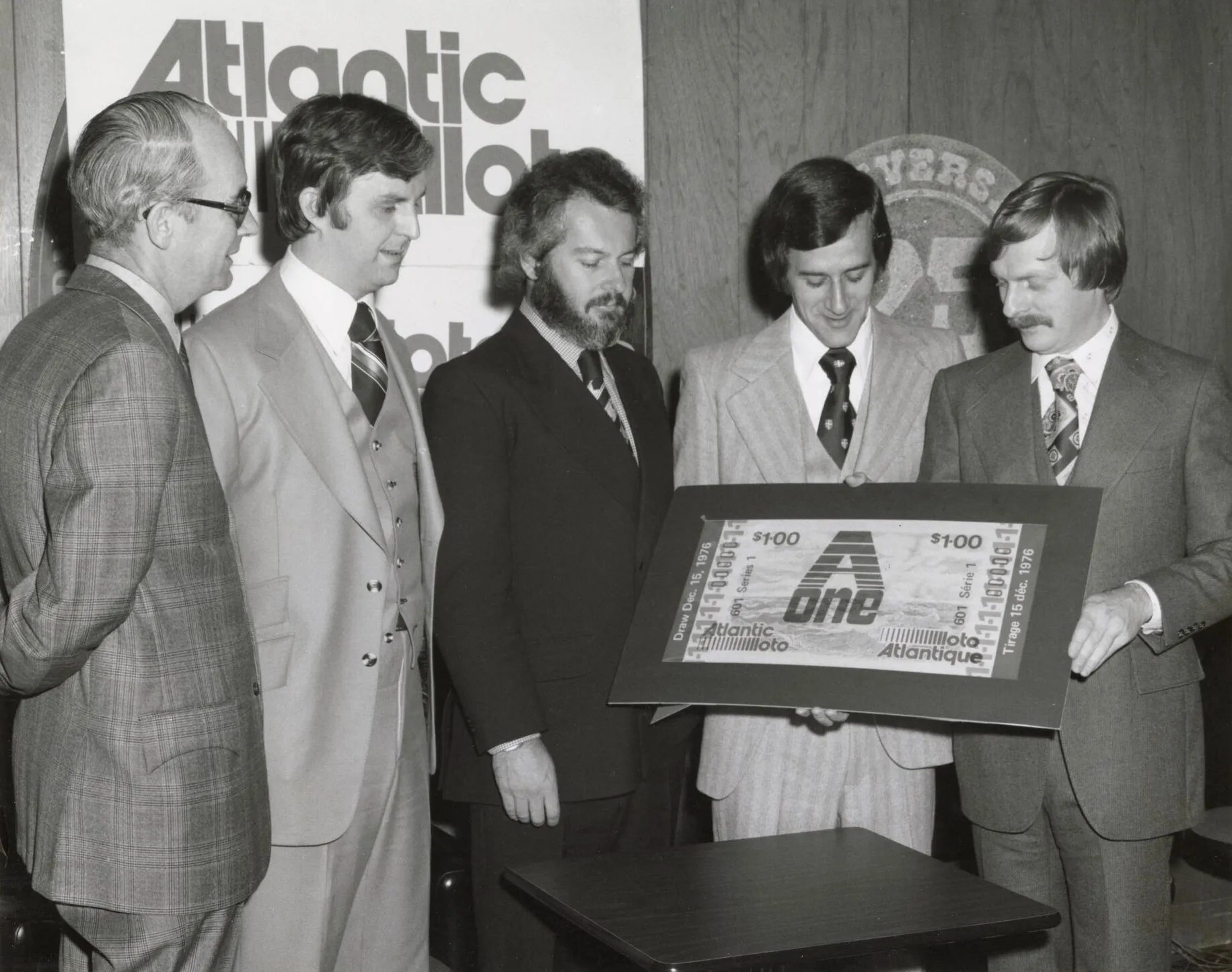 Jean-Marc Lafaille, le premier PDG de Loto Atlantique (à droite), dévoile un billet promotionnel pour A1, le premier et le seul jeu disponible à l’époque de la création de la société en 1976.